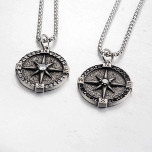 Detailed view of compass pendants with black and white rhinestones and retro metal texture