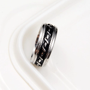 Détail d'une bague hip-hop en acier argenté avec bande noire et relief de chaîne