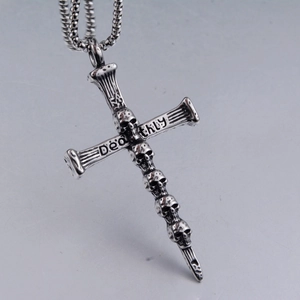 Gros plan du pendentif croix gothique en acier inoxydable avec crânes et gravure