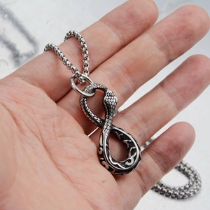 Macro view of silver vintage stainless steel snake infinity pendant on a thick chain