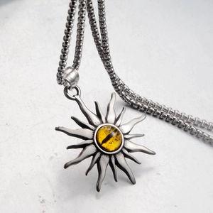 Dettaglio del ciondolo a sole vintage con occhio di drago giallo e texture metallica