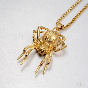 Close-up of golden spider pendant with detailed grain texture and gold box chain