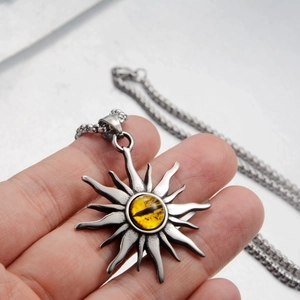 Dettaglio del ciondolo occhio di sole con pietra gialla su catena in acciaio inox