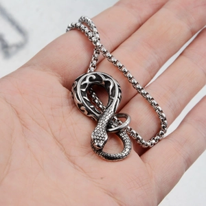 Detailed macro view of silver snake infinity pendant held on palm showing scales