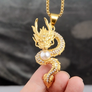 Detailed close-up of golden dragon pendant with white pearl and sparkling crystal inlay