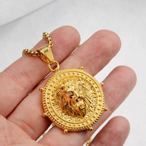 Detailed close-up of a golden stainless steel lion head pendant held in hand for scale