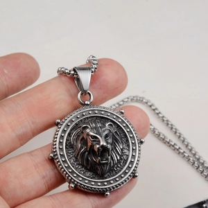 Detailed close-up of a stainless steel lion head relief medallion with a box chain