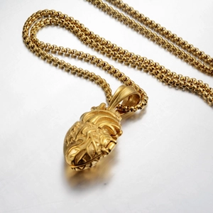 Nahaufnahme des goldenen anatomischen Herzanhängers mit Boxkette auf grauem Metall