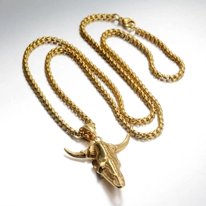 Close-up of a punk style golden bull skull pendant with a thick metal chain