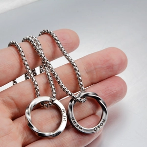 Dettaglio dei pendenti ad anello di Mobius con incisione New Here Road e catene box