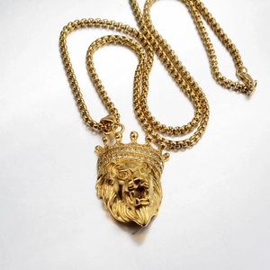 Macro shot of gold lion head pendant with rhinestone crown on a box chain necklace
