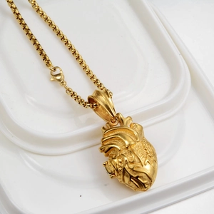 Detailansicht des goldenen anatomischen Herzanhängers mit realistischen Adern auf Perlenkette