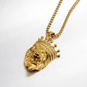 Macro shot of gold lion head pendant with crystal crown and elegant pearl chain
