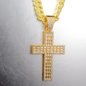 Détail d'un pendentif croix doré serti de zircons sur une chaîne à maillons cubains
