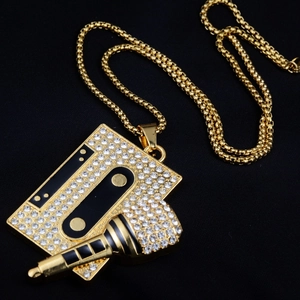 Gros plan du pendentif hip-hop doré avec cassette et microphone sertis de strass étincelants