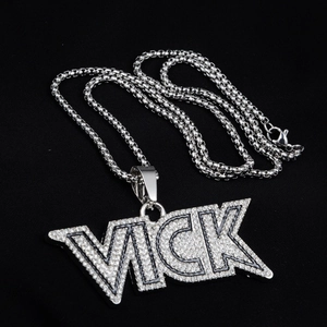 Dettaglio macro del ciondolo lettera VICK con cristalli bianchi su collana a catena silver