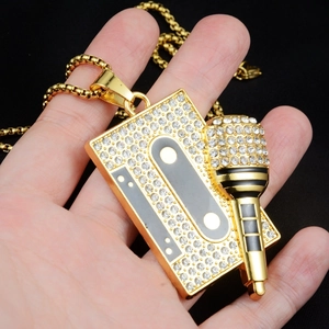 Gros plan d'un pendentif hip-hop plaqué or avec cassette, microphone et cristaux