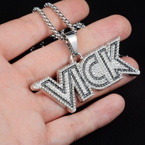 Dettaglio del ciondolo con lettera VICK con micro-pave di cristalli e catena a box