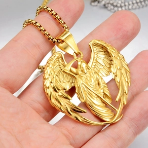 Macro détaillée du pendentif faucheuse ailée dorée tenu à la main pour l'échelle et texture