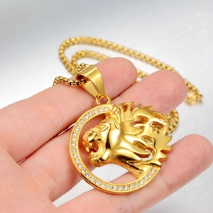Close-up van gouden leeuwenkop hanger met witte steentjes aan een stevige boxketting