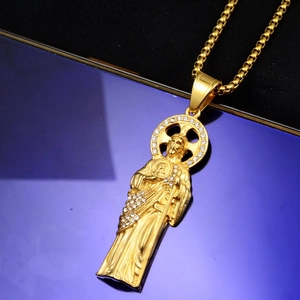Détail d'un pendentif religieux en or serti de strass sur une chaîne à mailles carrées