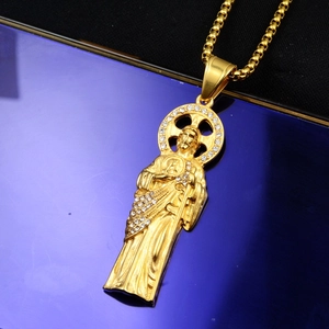 Gros plan d'un pendentif religieux doré serti de zircons blancs sur une chaîne maille