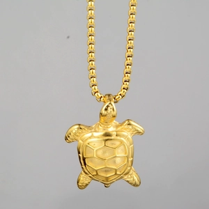 Detailed view of the golden turtle pendant with intricate shell texture on box chain