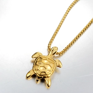 Detailed close-up of golden sea turtle pendant with geometric pattern and box chain
