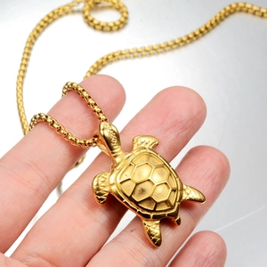 Macro shot of detailed golden sea turtle pendant with a sturdy box chain necklace