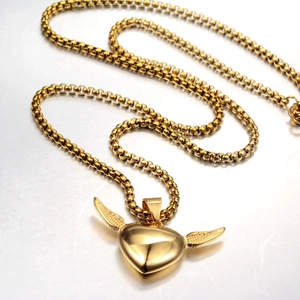 Detailed close-up of golden winged heart pendant with polished finish and box chain