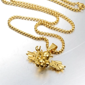 Detail of golden winged devil pendant with pitchfork on a metallic box chain