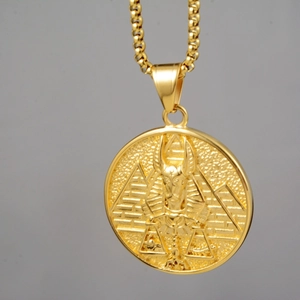 Detailed macro view of gold Egyptian Anubis and pyramid relief on round coin pendant necklace
