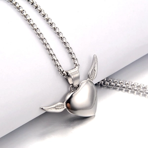 Macro detail of silver heart pendant with textured angel wings on a steel box chain