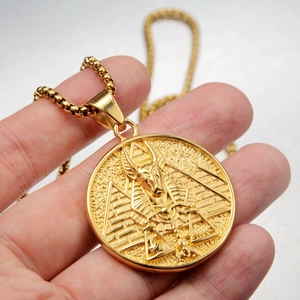 Detailed macro of gold Anubis relief pendant with ancient Egyptian motifs and ball chain