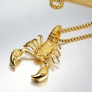 Macro shot of gold scorpion pendant with floral engraving on a square box chain