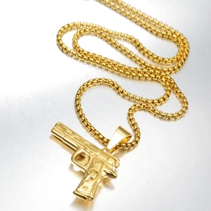 Detalle del colgante de revólver dorado con calavera grabada en collar de cadena box