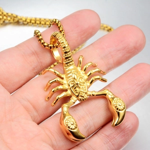 Macro detail of a golden scorpion pendant with intricate scales and square bead chain