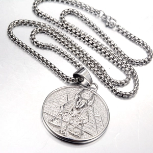 Macro shot of Egyptian Anubis and pyramid relief on a round silver pendant necklace
