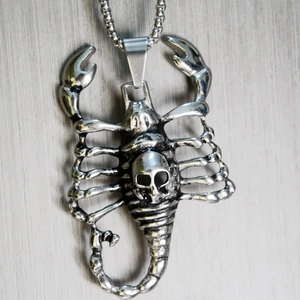 Macro shot of punk style scorpion pendant with skull motif on a metallic square link chain