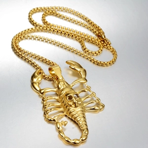 Macro shot of gold scorpion pendant with skull motif and chunky steel box chain