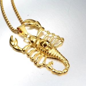 Detailed close-up of golden scorpion pendant with skull motif on a box chain necklace