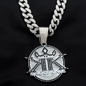 Detail of silver-toned hip hop pendant with crown and King of Kings text on cuban chain
