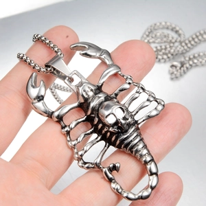 Detailed view of silver gothic scorpion pendant with skull motif on a box chain