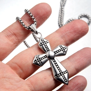 Detail shot of gothic silver cross pendant with black polka dots on a box chain
