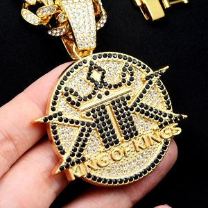 Detail of gold iced-out King of Kings medallion with black and clear stones on cuban chain