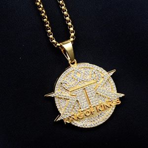 Close-up of gold hip hop pendant with crown motif and King of Kings text engraving