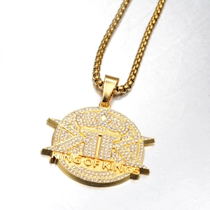 Macro shot of gold hip-hop pendant with King of Kings text and crystal crown detail
