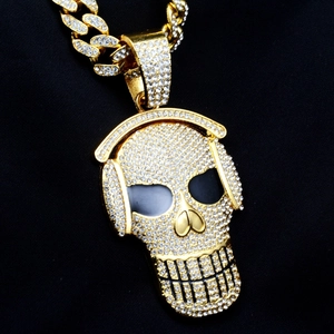 Macro detail of gold-toned skull wearing headphones pendant with pavé white zircons