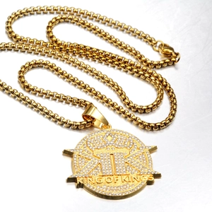 Macro shot of iced-out gold pendant with King of Kings text and crown detail