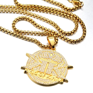 Close-up of gold hip-hop pendant with crown design and King of Kings engraving